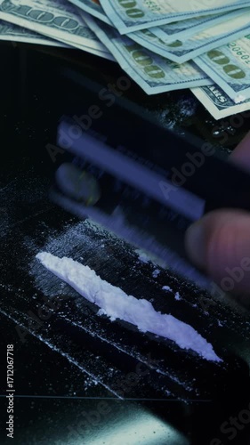 Addict makes lines of white powder with bank card on black table. Vertical video