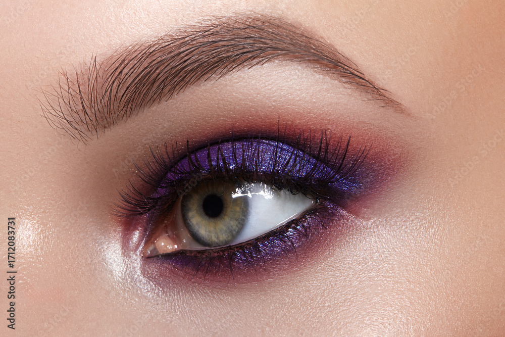 Fototapeta premium Macro of bright purple eye make-up. Celebrate Makeup for fashion show, bride wedding style. Perfect for Beauty salon, Makeup Artist or Cosmetic store Advertising. Glowy Skin, perfect brows shapes