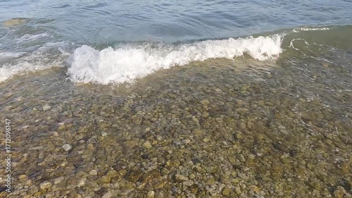 Foaming waves splashing on the pebble beach. Slow motion.