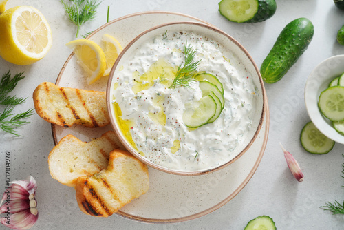 Tzatziki salad with roasted bread in white bowl on white background. Homemade Tzatziki salad with olive oil. Top view.
