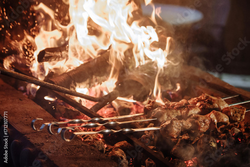 Grilled meat on skewers over a vibrant open fire