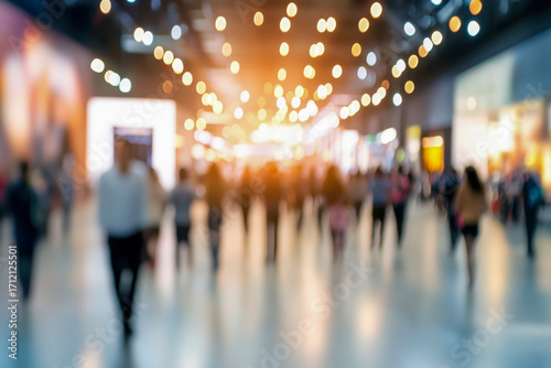 Crowds of people move through a brightly lit indoor space, creating a lively atmosphere with a sense of motion and excitement
