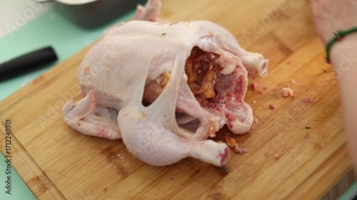 A woman is preparing a meal by carefully stuffing a whole chicken in her kitchen. The video shows the step-by-step process of home cooking, creating a cozy and appetizing atmosphere.