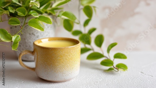 Golden turmeric latte in a ceramic mug, beside a potted plant