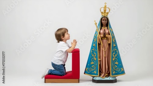 Small child kneels in prayer before the statue of Nossa Senhora Aparecida in a serene setting