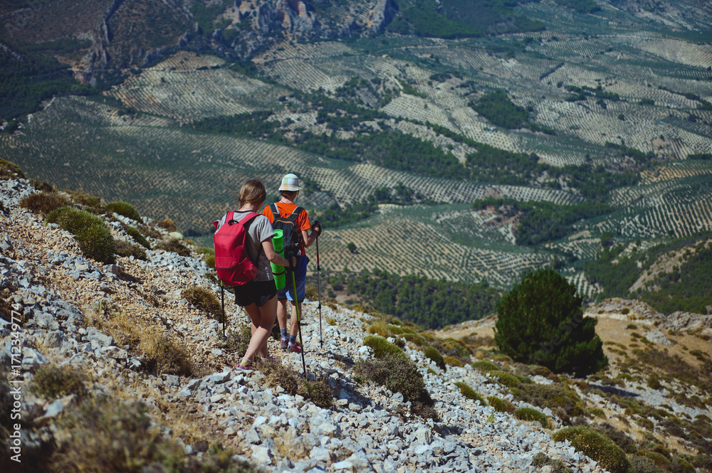 Obraz premium Hikers Exploring Rocky Terrain Amid Stunning Views of Agricultural Valleys