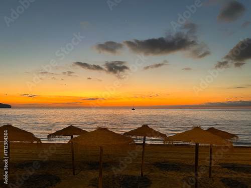 Sunset at sea. Sunset at sea. Straw beach umbrellas. Photo