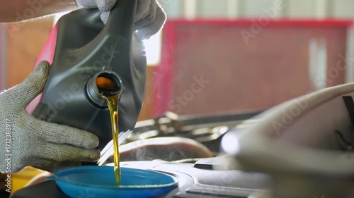 Pouring Oil: Close-up of gloved hands carefully pouring fresh oil into a car engine during maintenance.