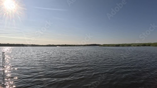 Scenic aerial view of a lake at high speed. The sun's rays reflect on the sparkling water surface with waves and ripples. A high-speed flight over the river.