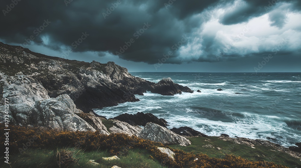 Fototapeta premium Dramatic coastal landscape with dark storm clouds looming over rocky shore and turbulent waves crashing