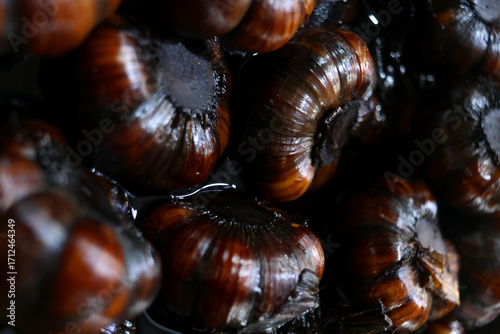 Photos Glossy, dark bulbs of black garlic sit in syrupy liquid, their outer skins caramelized to mahogany