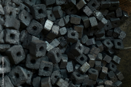 Foto A spread of perforated charcoal briquettes—small square coals with a central hole for airflow—fills the frame