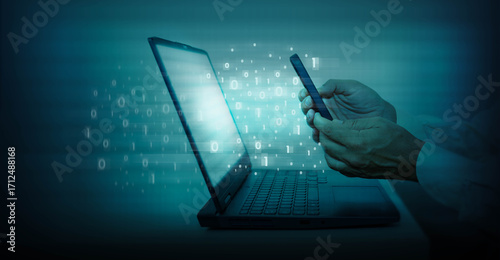 Man using mobile phone and laptop computer with binary code on blue background. Concept of digital data transmission between devices.