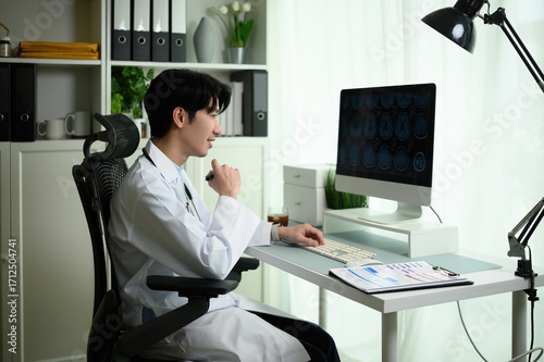 A Focused Neurologist specialist interprets Brain MRI imaging on computer screen with expert attention, seated in a hospital office environment