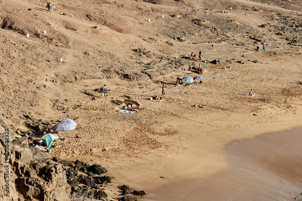 Obraz premium Golden sandy beach with sunbathers and surfers in El Cotillo, Fuerteventura, Canary Islands
