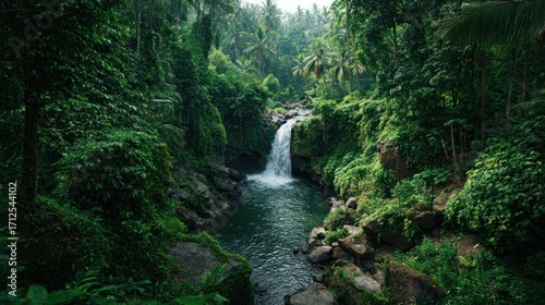 Lush tropical waterfall cascading into a rocky stream, surrounded by dense green foliage and towering trees