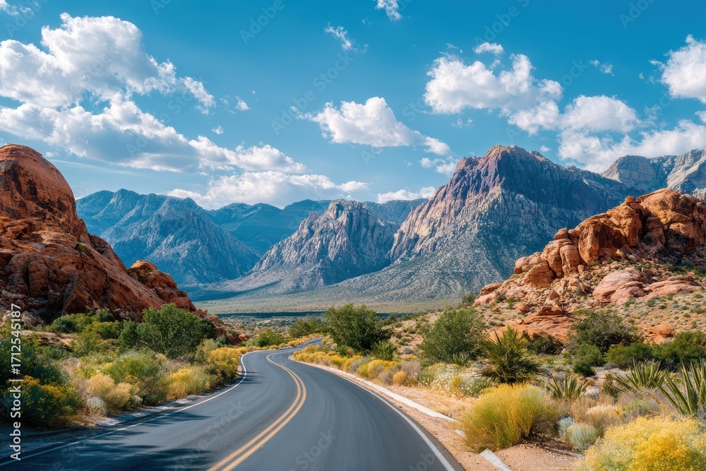 Fototapeta premium Scenic Road Through Red Rock Canyon with Majestic Mountains and Blue Sky, Natural Beauty in a Desert Landscape, Vibrant Colors and Dramatic Clouds
