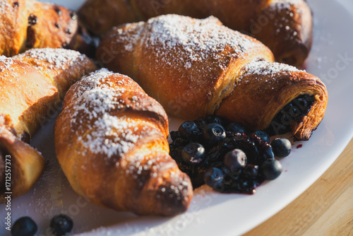 to the breakfast - homemade croissant filled with blueberry jam, served on a white plate