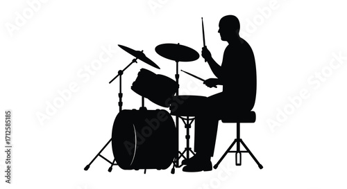 A drummer energetically playing a drum kit in dark silhouette