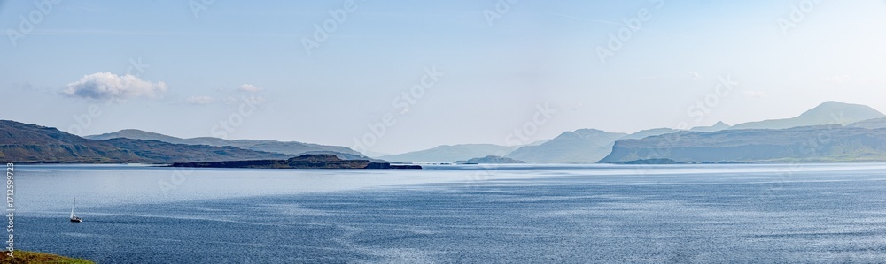 Fototapeta premium Panoramablick von Staffa zur Isle of Mull – sonnige Küstenlandschaft mit blauem Meer und Bergen im Hintergrund, aufgenommen im August 
