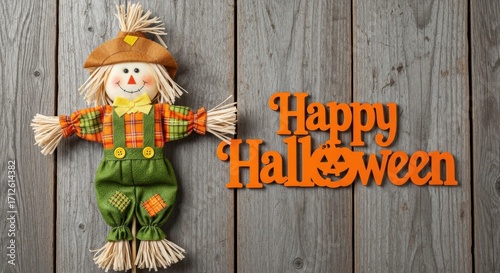 Cute scarecrow decoration with happy halloween text on wooden background