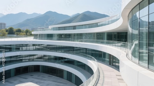 Modern curved glass building with multiple levels and mountain backdrop