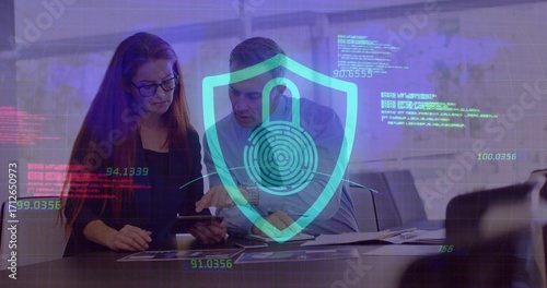 Male and female colleagues analyzing data on tablet in meeting room, with digital security graphics