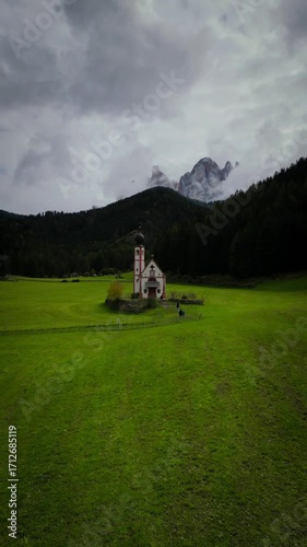Luftaufnahme der Kirche Santa Magdalena vor der Kulisse sanfter grüner Hügel und majestätischer Berge, Val di Funes, Trentino-Südtirol, Italien.