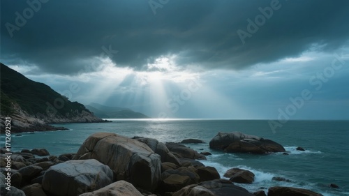 Dramatic coastal scene with sun rays piercing through storm clouds over rocky shoreline