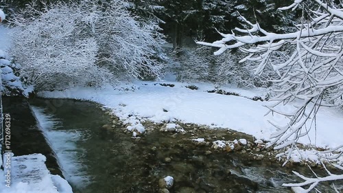 Flowing water of cascade waterfall in winter forest.