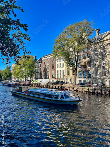 Canvas Print A serene canal tour in Amsterdam, with boats navigating through the city's pictu
