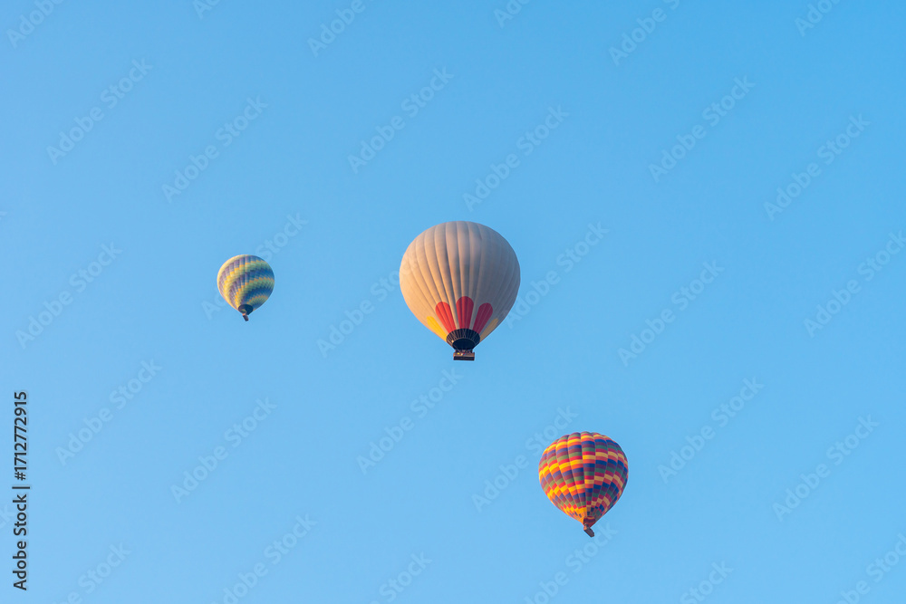 Obraz premium Three hot air balloons against a blue sky. Beautiful view of colourful hot air balloons from below. Cappadocia