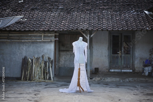 Elegant white wedding dress displayed on a mannequin in an outdoor rural setting