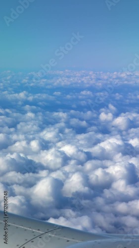 4K, Beautiful clouds from above, as seen through airplane window. Traveling by air. View of traveler in cabin at turbine and plane wing in flight trip with blue sky. 
