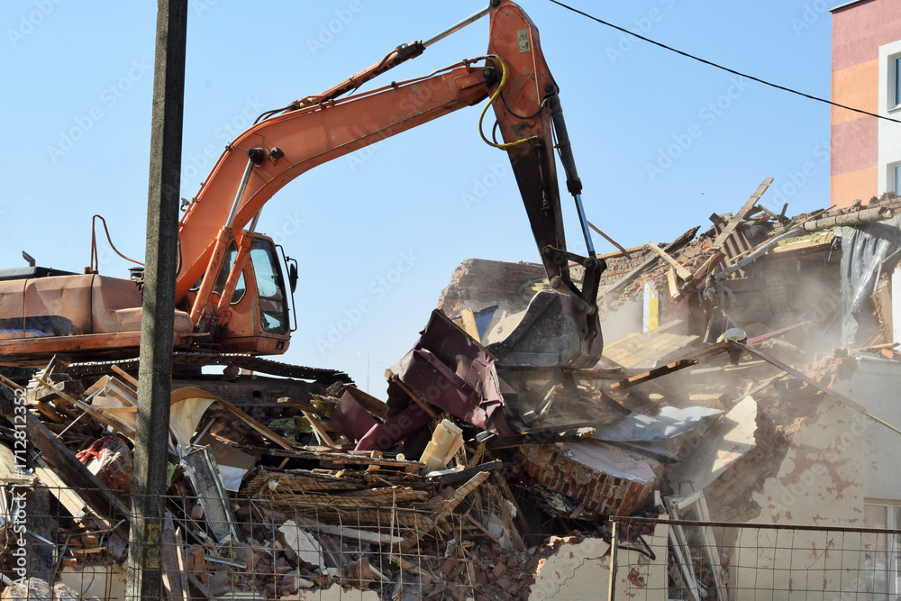 Fototapeta premium A modern excavator removes the rubble of a demolished residential building.
