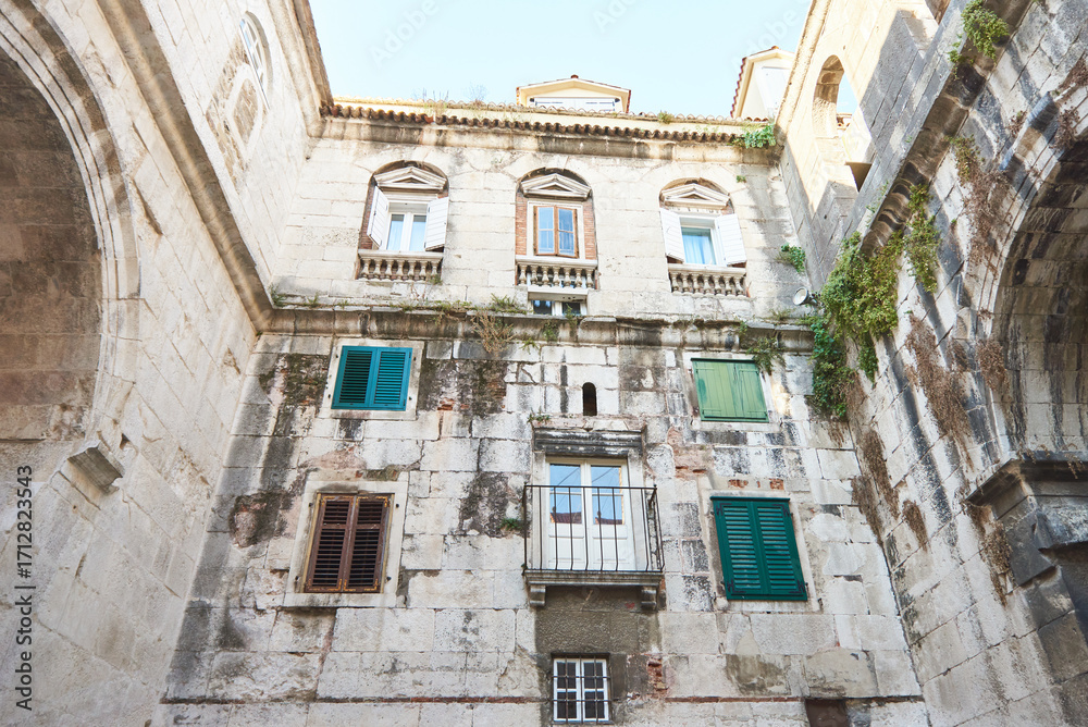 Obraz premium Different windows and green shutters on an old croatian building facade