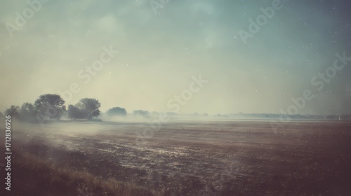 Flat rural field under cloudy sky, presenting a calm agricultural landscape suited for rustic or nature-related themes.
