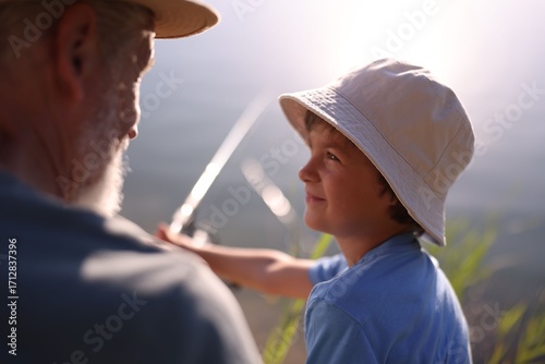 Obraz na plátně Grandfather and his nephew fishing together outdoors, closeup