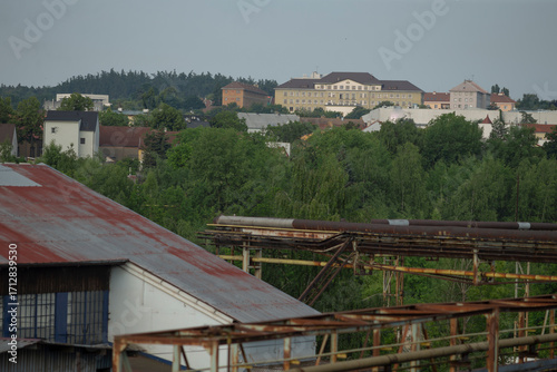 A blend of industrial structures and lush greenery, capturing the contrast between nature and man-made environments in a serene setting.