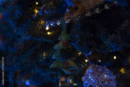 A beautifully decorated Christmas tree featuring a green tree-shaped ornament and twinkling lights, creating a cozy holiday atmosphere.