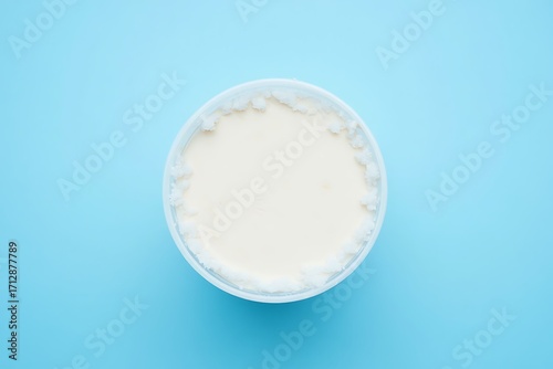 Top view of a bowl of white cream on a blue background