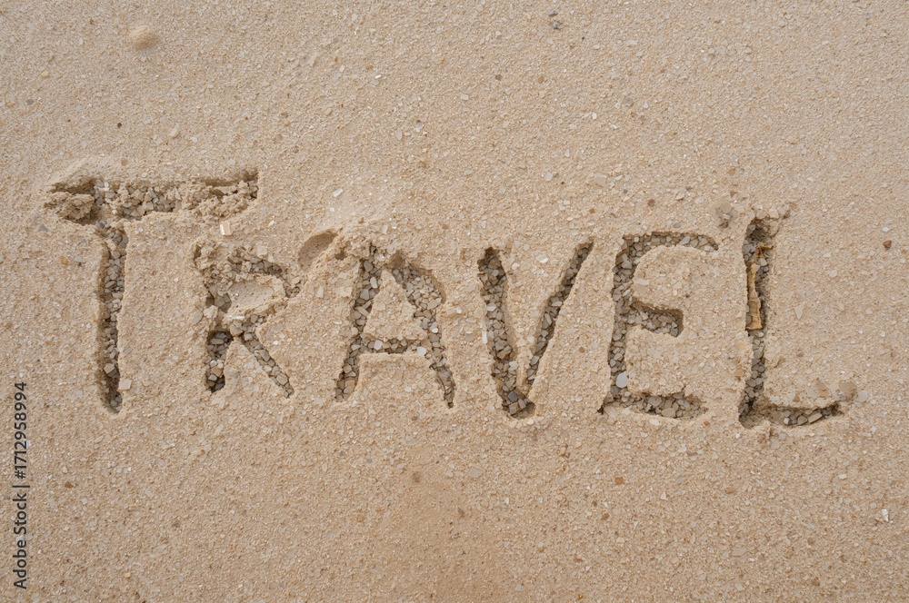 Fototapeta premium Alphabet of the word 'travel' etched in golden sand on a sunny beach