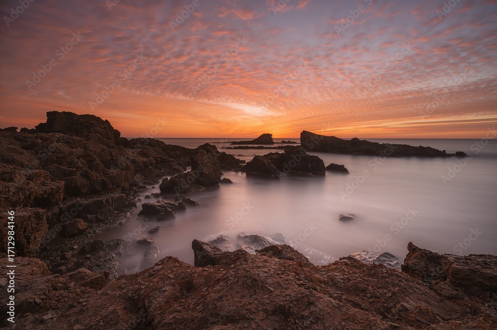 Obraz premium Beautiful long exposure sunset over a rugged shoreline. Scenic natural view.