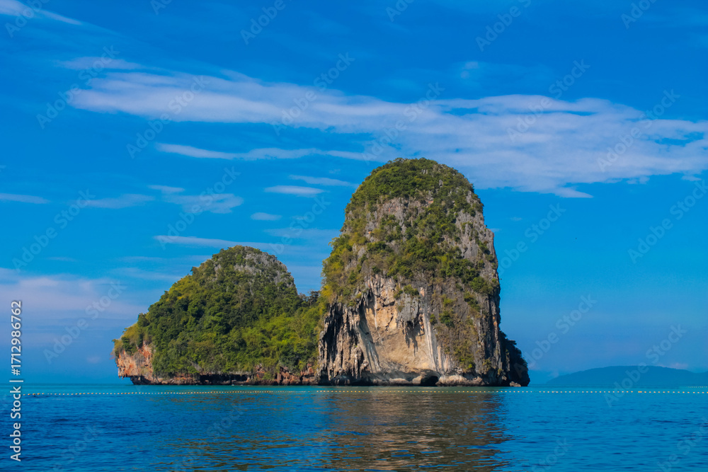 Fototapeta premium Cliffs, palm trees and sandy beach in Krabi, Thailand, with turquoise sea, limestone formations, and tropical vegetation under clear sky, showing coastal landscape travel destination in Andaman sea