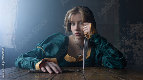 Fényképezés Young noble in green Renaissance finery grasps dagger, dangerous court politics implied