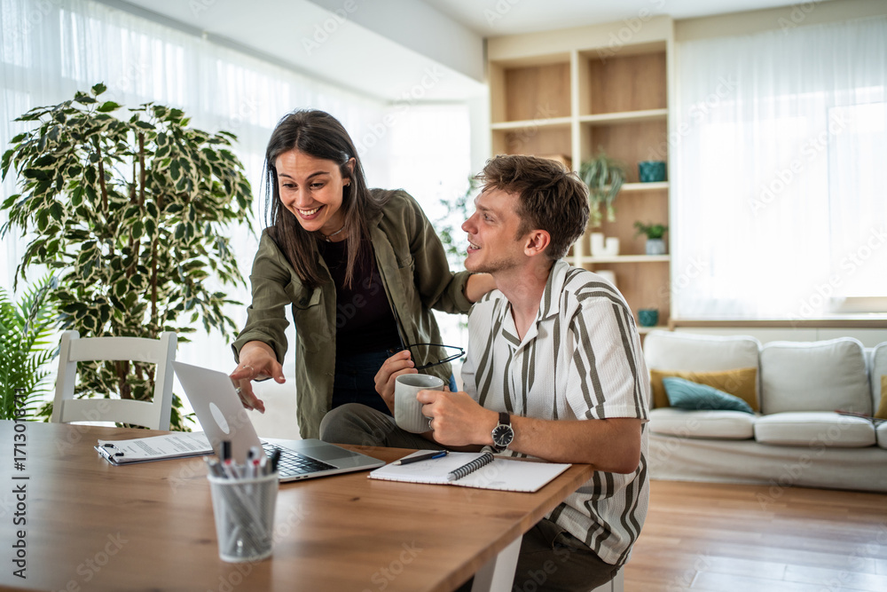 Obraz premium Couple collaborating on a laptop at home office
