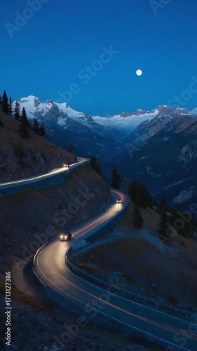 Drone aerial of winding mountain road with car headlights at night