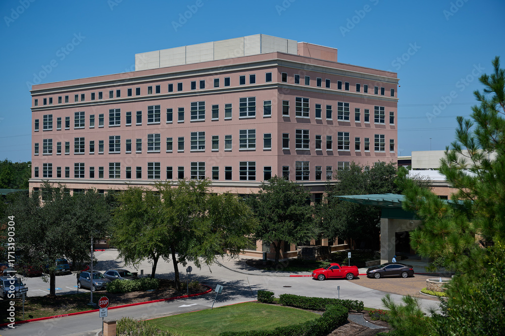 Obraz premium HOUSTON, TEXAS - SEPTEMBER 29th 2025: Sunlit hospital campus of St. Luke’s Health in The Woodlands, Texas. No people. Green landscaped grounds and modern medical buildings captured at midday.