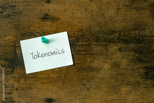 There is a piece of paper with the word Tokenomics. It is as an eye-catching image.