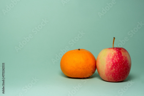 apple and orange or mandarin on plain green background